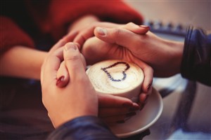 两双手拥着爱心拉花咖啡杯