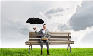 草原上打着雨伞坐在长椅上的商务人士高清图片 