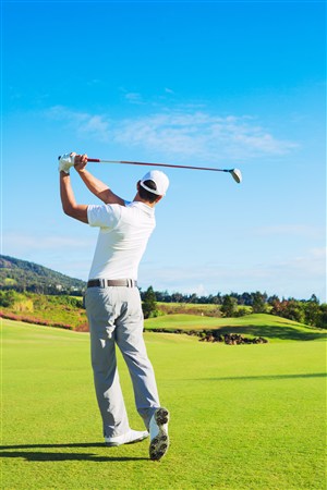 蓝天下草地上打高尔夫球的男士高清图片