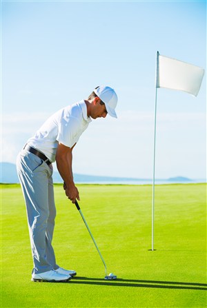 草坪上打高尔夫球的男士和旗杆高清图片