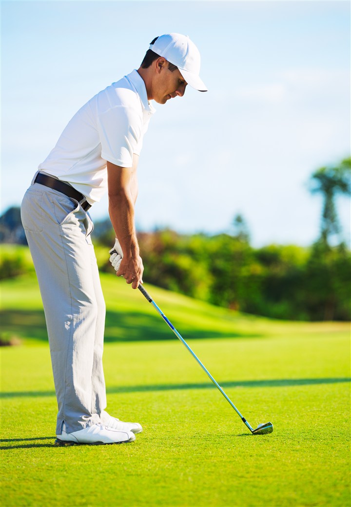在绿色草坪上打高尔夫球的男士高清图片