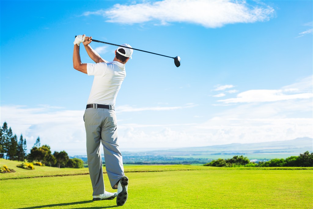 蓝天白云下挥杆打高尔夫球的男士背影高清图片