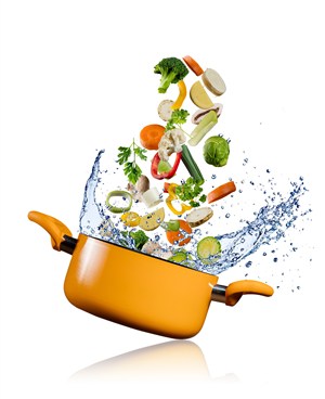 黄色汤锅里漂浮的蔬菜和飞溅的水花高清图片