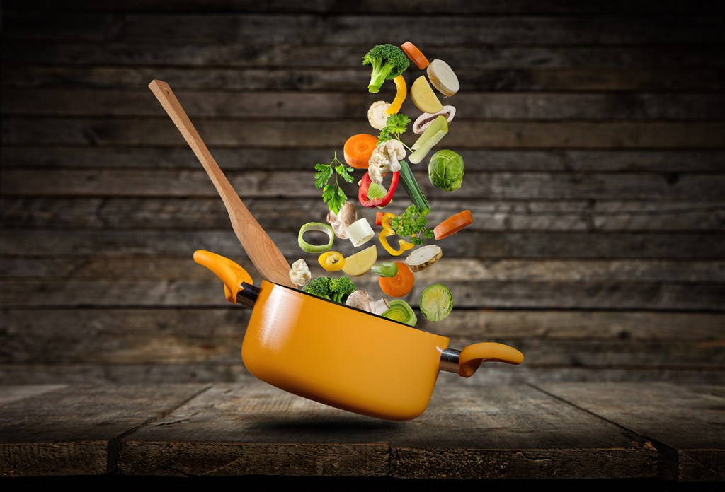 木桌上的汤锅和漂浮的蔬菜高清图片