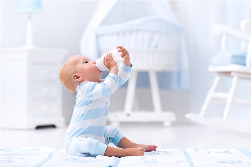 坐在地上抱着奶瓶喝奶的小宝宝