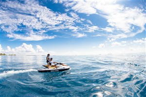 蓝天白云下大海上开摩托艇的情侣图片