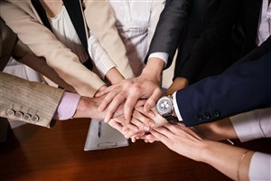办公桌上多人团队合作握手手势图片