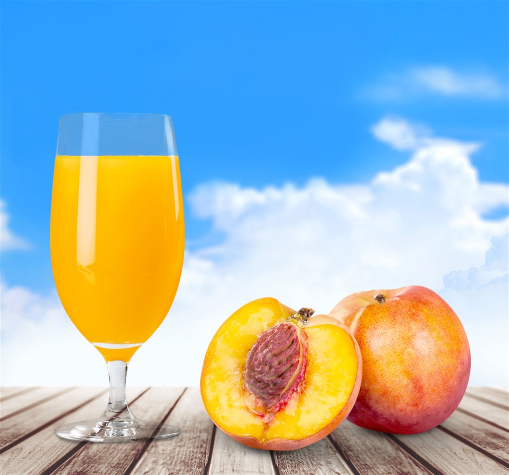 蓝天白云下的黄桃和高脚杯里的果汁高清图片