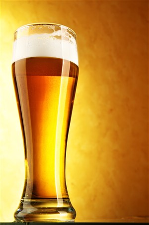 黄色背景下装满了啤酒的酒杯 