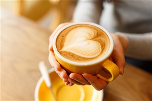 双手拖着爱心拉花的咖啡杯图片
