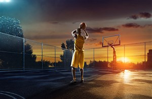 夕阳下正在练习的篮球运动员 