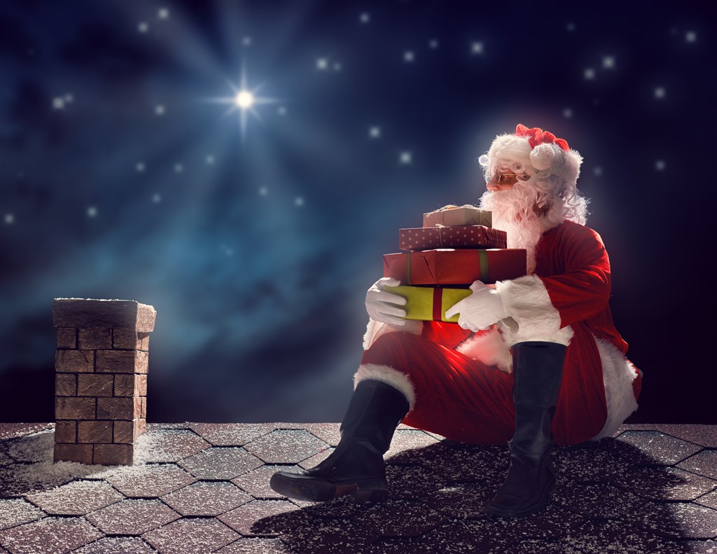 抱着礼盒坐在屋顶上的圣诞老人