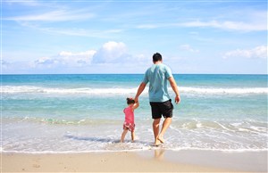 蓝色旅游温馨父亲带女儿在海边沙滩玩耍