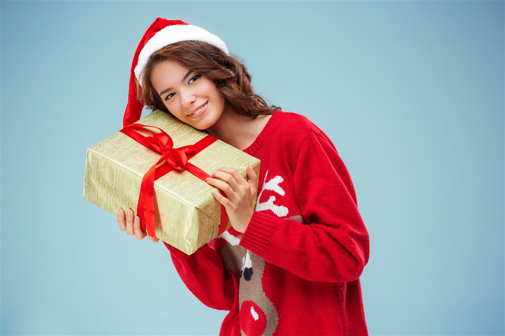 把礼物放在肩上的圣诞老人装扮的女生高清摄影图片