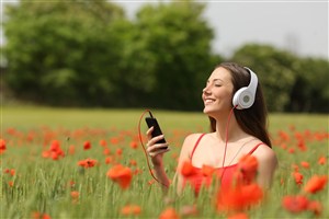 花丛中戴耳机听音乐的外国女性高清摄影图片