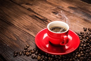 咖啡豆旁边冒着香气的红色咖啡杯高清摄影图片