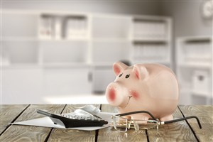 眼镜和计算器旁边的小猪存钱罐高清摄影图片