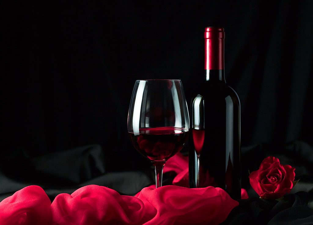 在玫瑰花边上的红酒瓶高清摄影