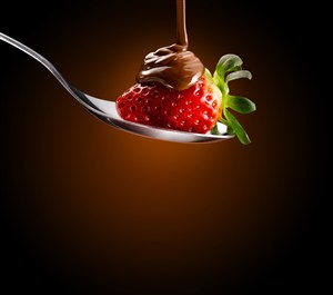 勺子里正在往草莓上面加巧克力酱的高清摄影图片